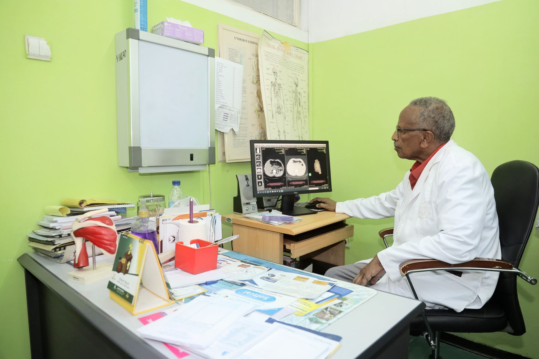 A doctor reviewing scans on a computer in his consulting room