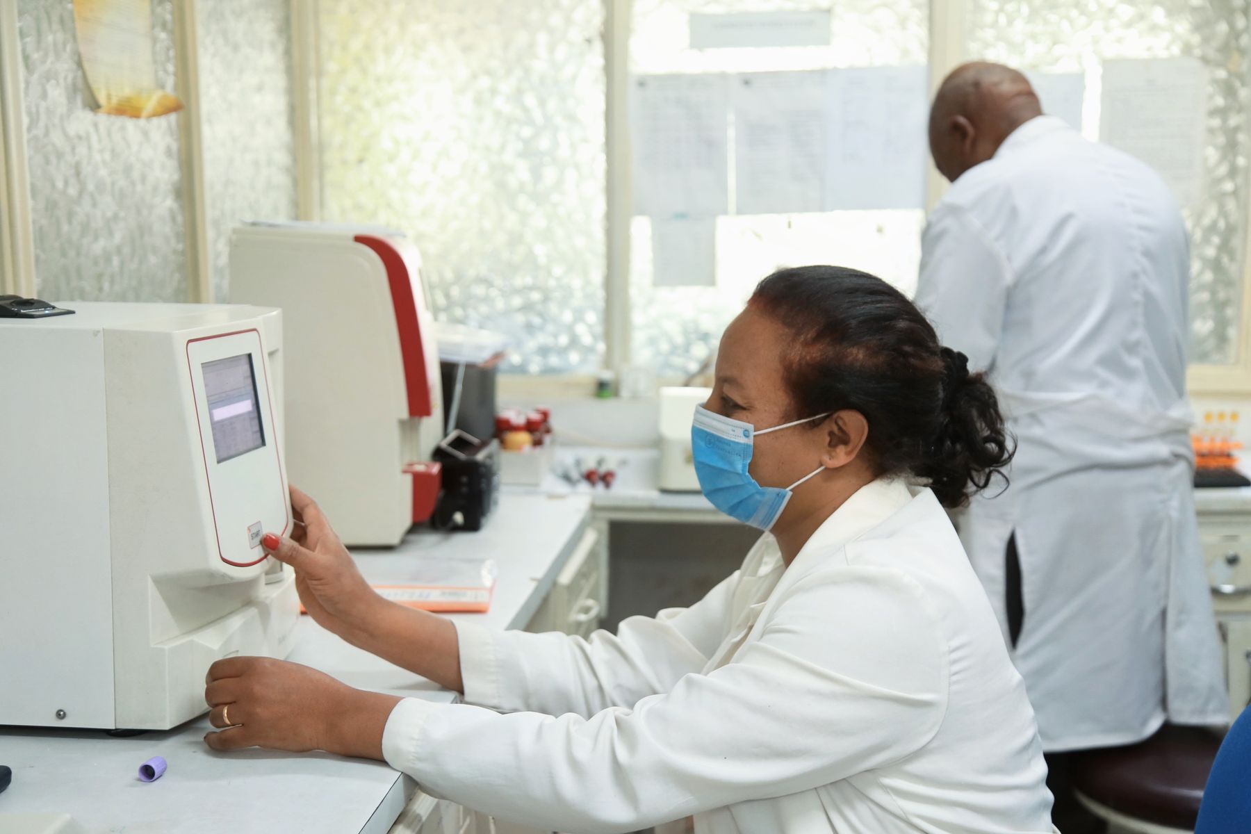 A laboratory technician running a blood sample on an analyser