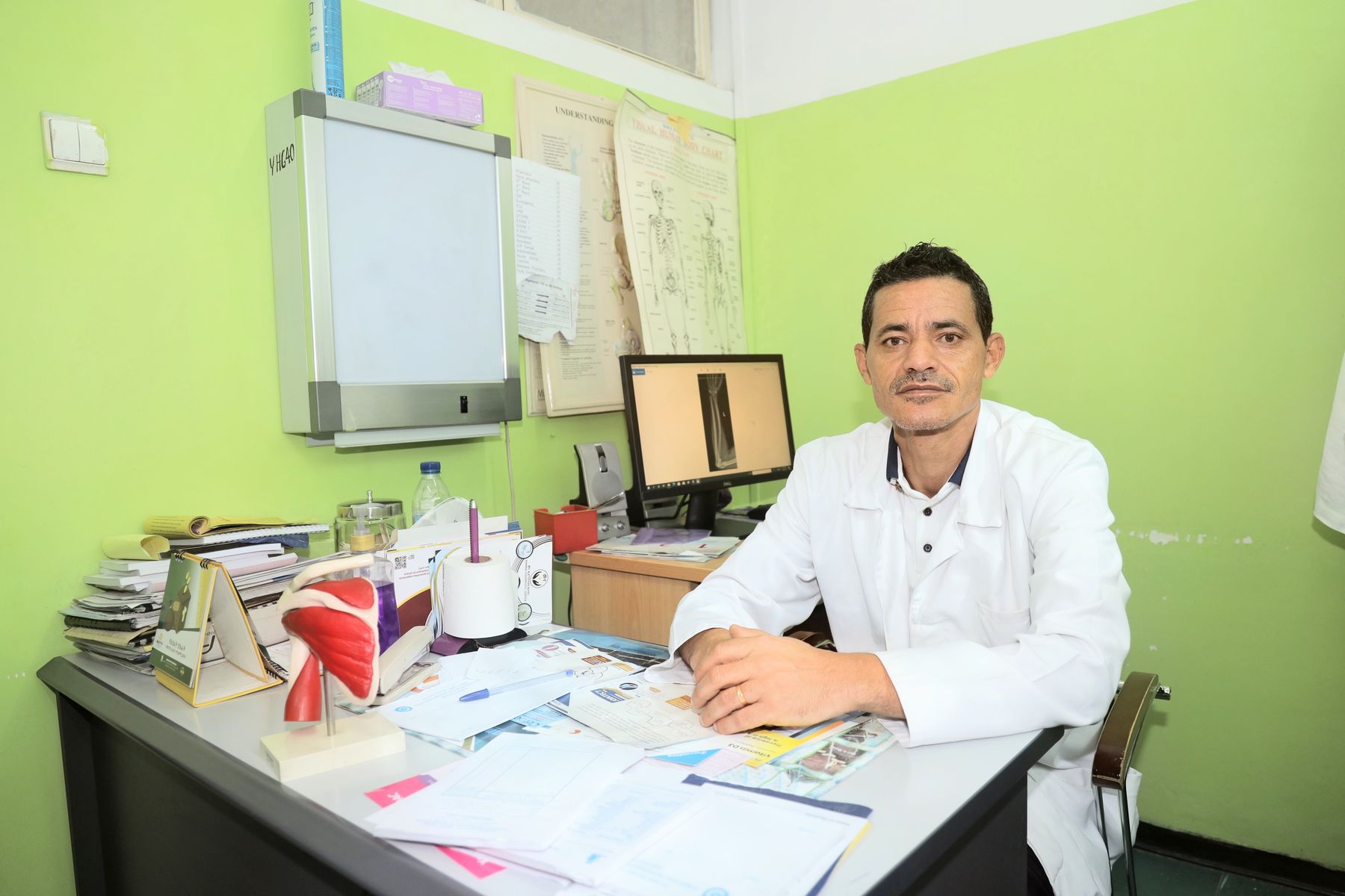 A doctor seated at his desk in an outpatient consultation room