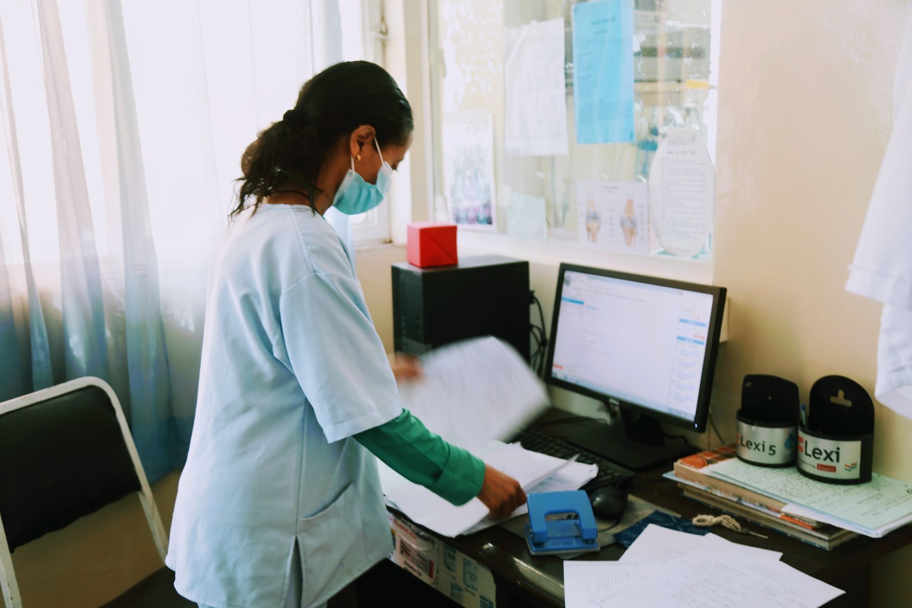 A nurse working at the records and registration computer
