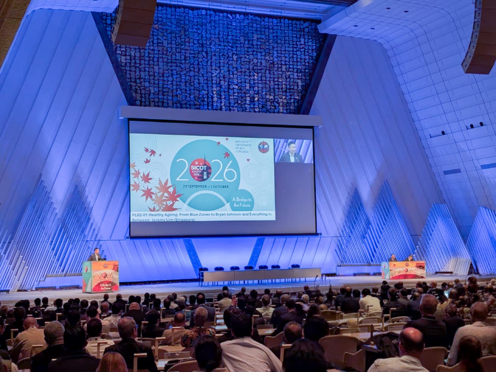 A plenary session in the main hall of the 46th SICOT World Congress in Kyoto, with the 2026 congress banner on screen